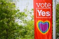 The city of Sydney council supporting same-sex marriage with heart rainbow by a flag on a light pole `vote yes` banners.